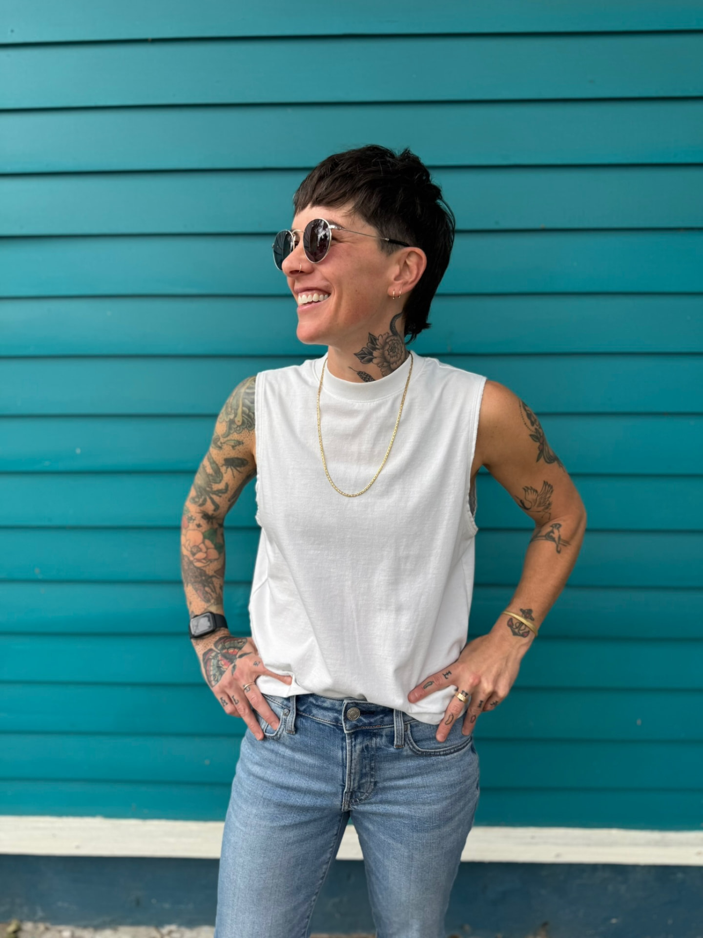 Kelly, founder and strategist at Broccoli Media, smiling in front of a teal clapboard wall in New Orleans